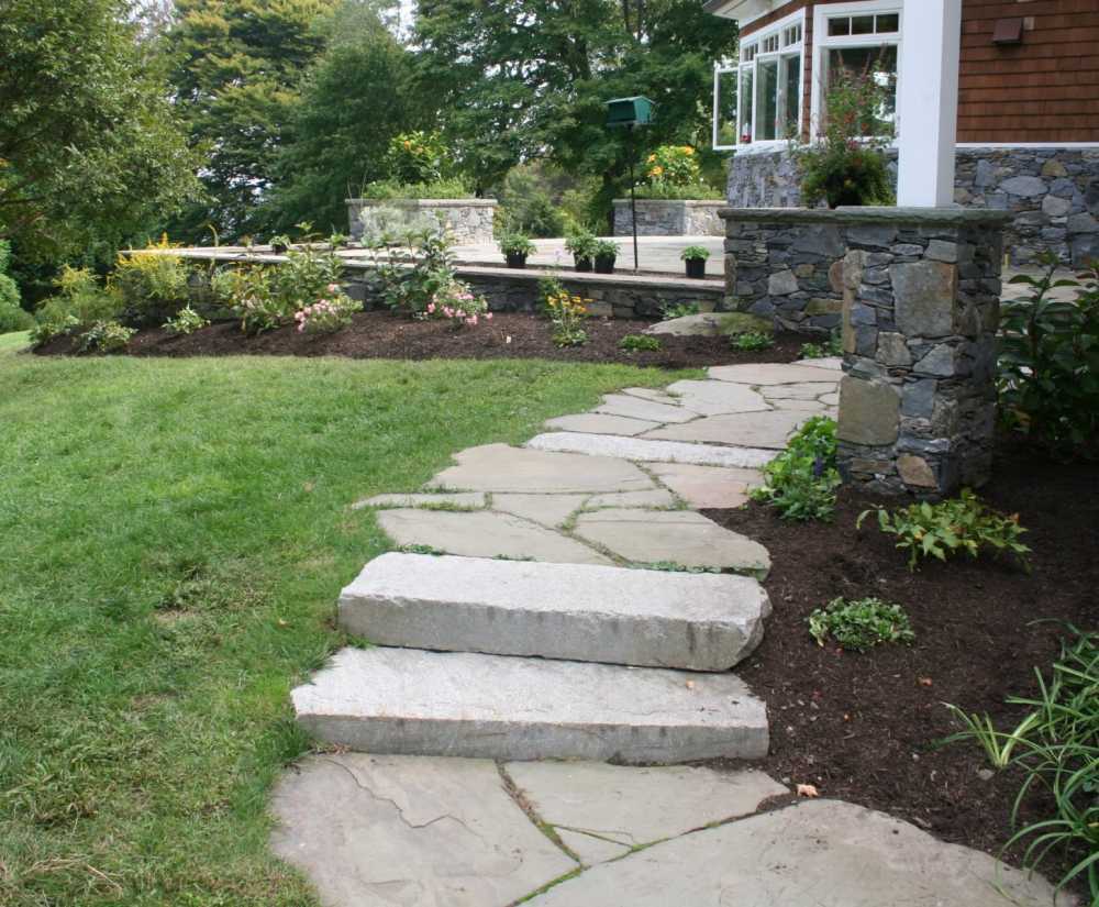 A flagstone path with slab steps lead to this backyard patio.  Stone pillars were built to support a second floor deck.